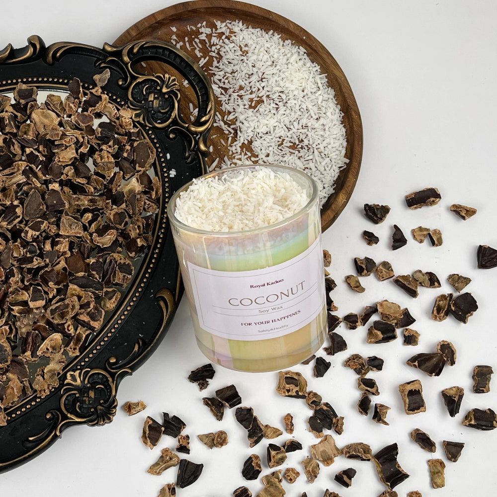 Candle labeled 'Coconut' surrounded by coconut flakes and dark chocolate pieces on a white surface.
شمعة جوز الهند المعطرة من شمع الصويا داخل عبوة زجاجية أنيقة، محاطة بجوز الهند المجفف في تنسيق ديكوري مميز.