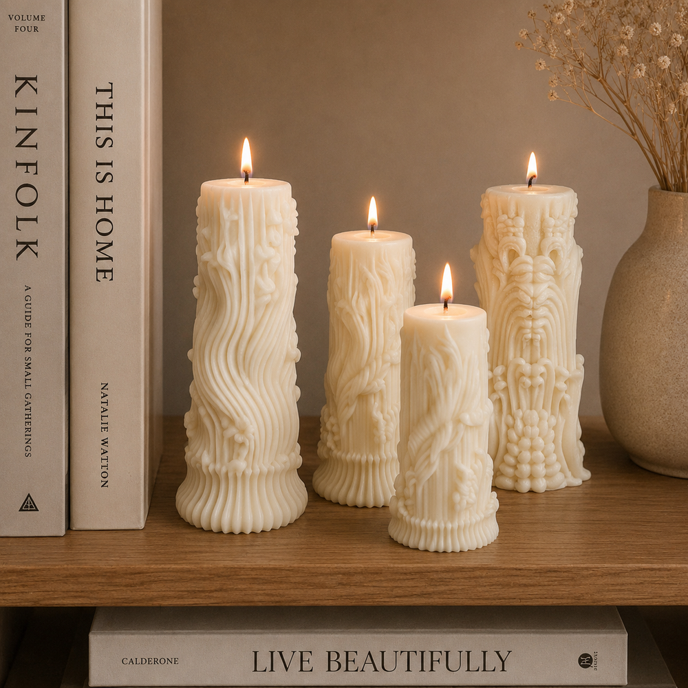 Four cream-colored pillar candles with intricate 3D embossed floral and vine patterns, arranged on a wooden shelf next to books and a vase with dried flowers.
طقم شموع ديكور كريمي من 4 قطع بتصميمات منحوتة ونقوش بارزة مختلفة لتزيين الكونسول والأرفف والمنزل.