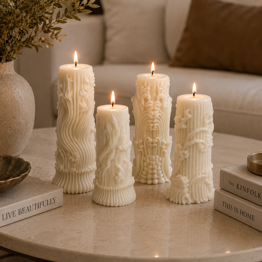 Four tall cream-colored decorative pillar candles with intricate embossed floral and scroll patterns, lit and arranged on a light marble coffee table in a cozy living room setting.
طقم شموع ديكور كريمي من 4 قطع بتصميمات منحوتة ونقوش بارزة مختلفة لتزيين الكونسول والأرفف والمنزل.