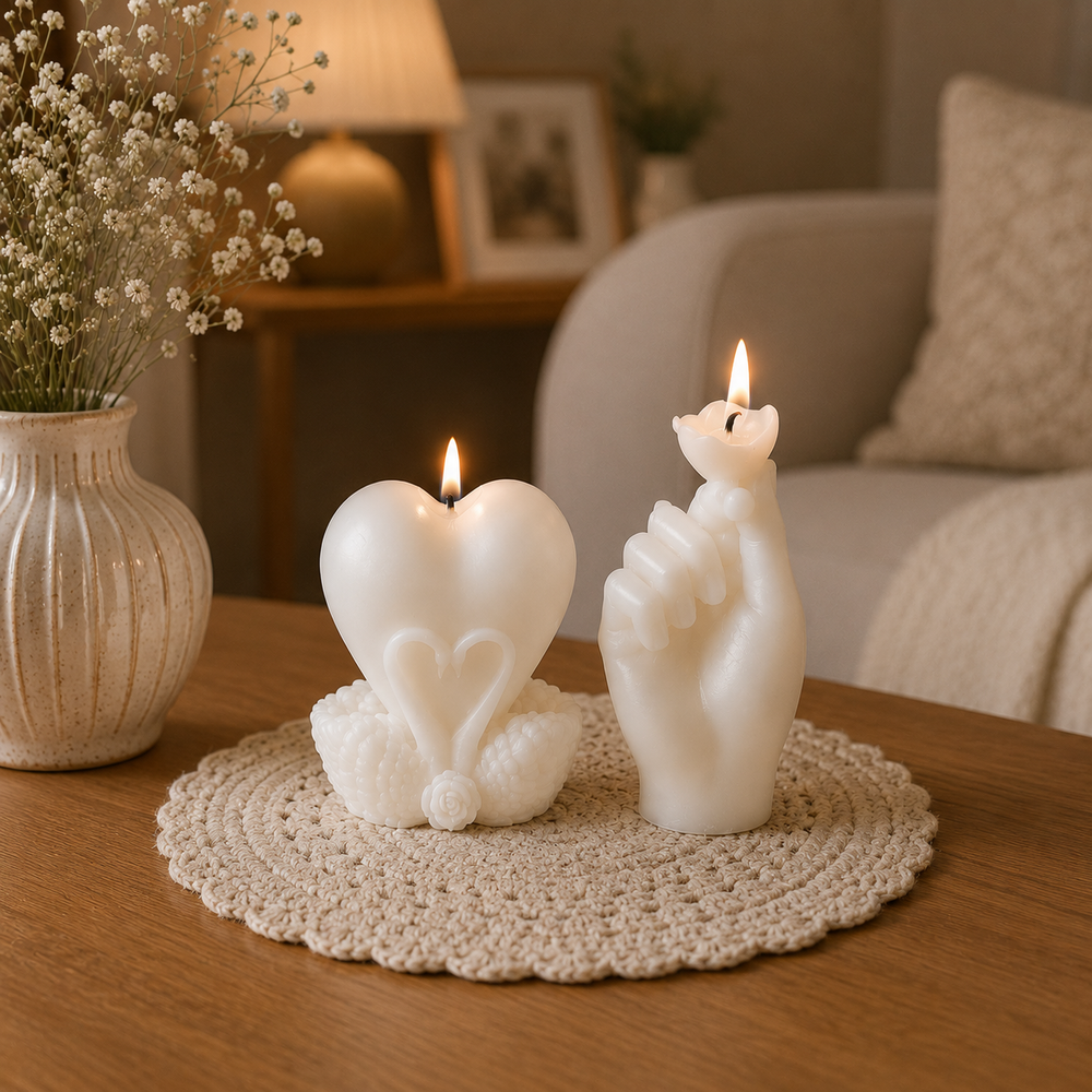 Two white sculptural candles on a round woven placemat on a wooden table in a cozy living room. One candle is shaped like a heart with a smaller heart motif inside, and the other is shaped like a hand holding a small 
flame.
طقم شموع ديكور كريمي بتصميم قلب ويد رومانسية، منسق على طاولة خشبية داخل غرفة معيشة بديكور هادئ ومودرن.