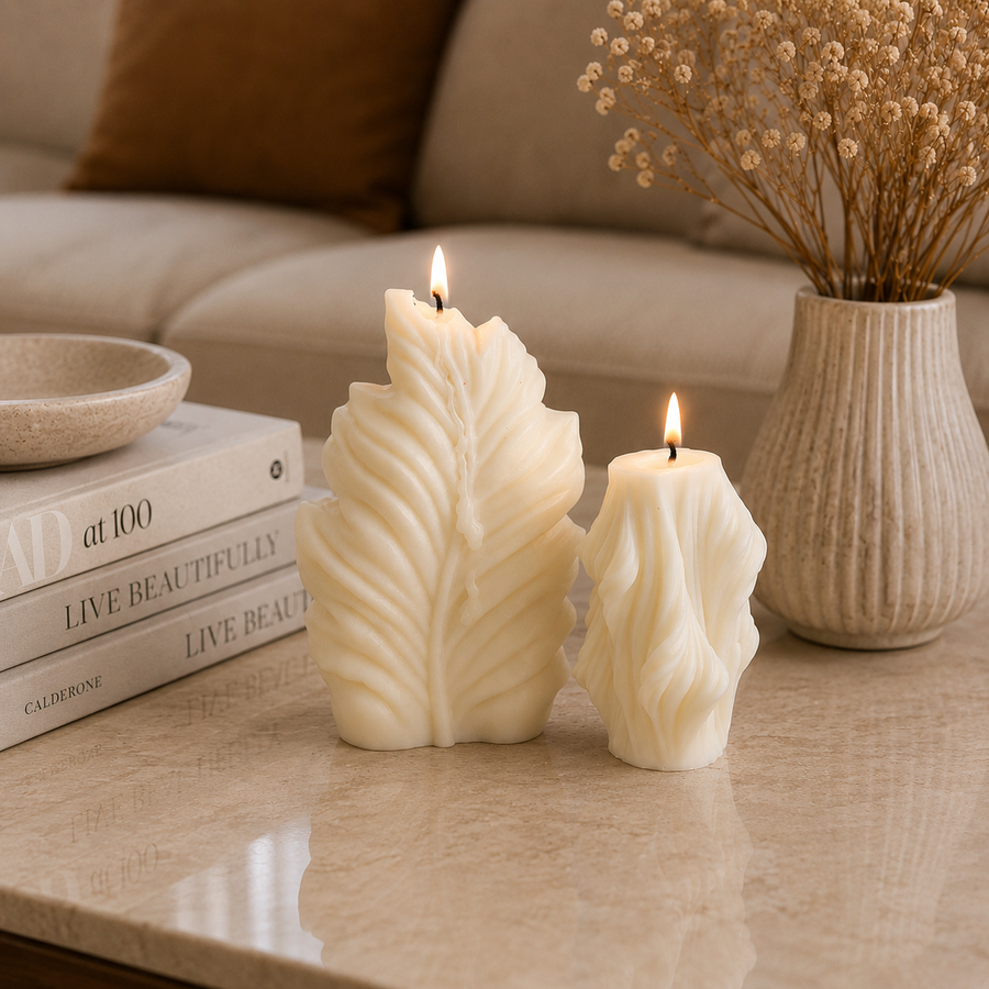 Two cream-colored leaf-shaped candles, one large and one small, lit on a beige marble table in a cozy living room setting.
طقم شموع ديكور أوراق الشجر كريمي من قطعتين بأحجام مختلفة وتصميم منحوت مستوحى من الطبيعة للكونسول والأرفف.
