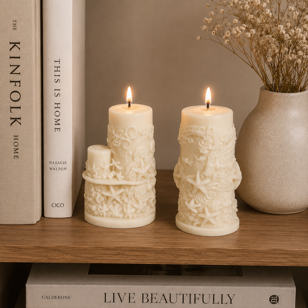 Two cream-colored, sea-creature embossed pillar candles are lit on a wooden shelf, styled with books and a ceramic vase of dried flowers.
طقم شموع ديكور كريمي من قطعتين بتفاصيل بحرية بارزة مستوحاة من الأصداف والنجوم لتزيين المنزل والكونسول.