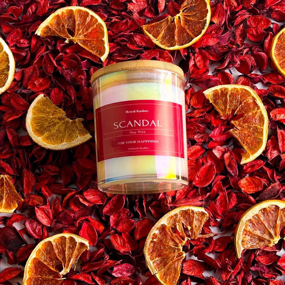 Candle labeled 'Scandal' surrounded by dried orange slices and red flowers
شمعة سكاندال معطرة من شمع الصويا داخل عبوة زجاجية بغطاء خشبي، محاطة بزهور حمراء وشرائح برتقال مجففة.
