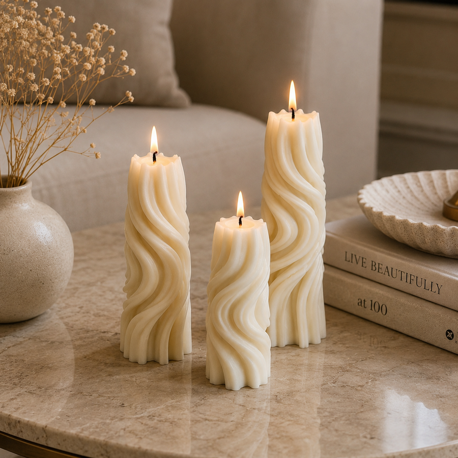 Three cream-colored twisted pillar candles with lit flames, styled on a marble table next to a vase of dried flowers and books.
طقم شموع ديكور مودرن مكون من 3 شموع بتصميم حلزوني وأحجام مختلفة باللون الكريمي لتزيين الكونسول والأرفف.