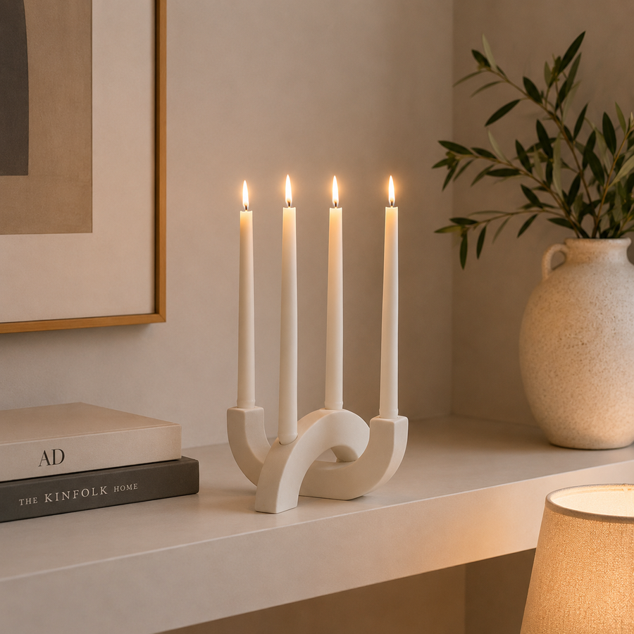 White four-arm sculptural candlestick holder with four matching white taper candles, styled on a woven table runner in a modern dining room for elegant home décor.