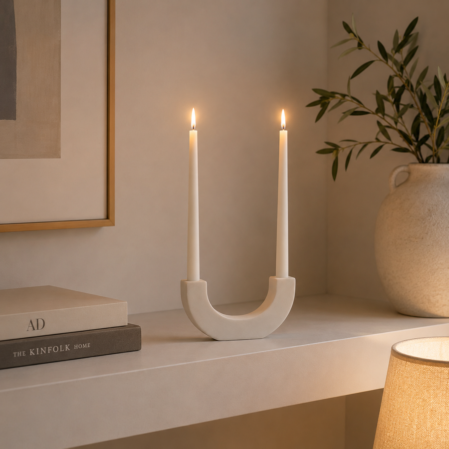 White U-shaped sculptural candlestick holder with two matching white taper candles,